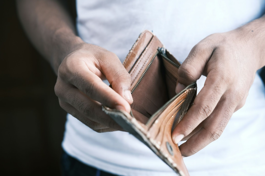 Close-up of a man’s hands holding an empty tan-coloured wallet