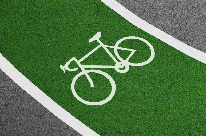 Close-up of a green cycle track which features a white graphic outline of a bicycle